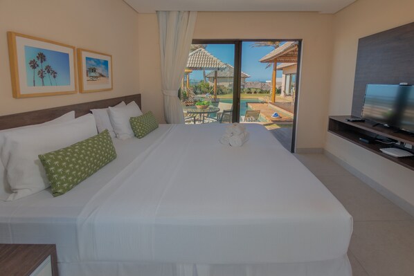 A hotel room with a large bed, a TV, and a view of a pool and outdoor area.