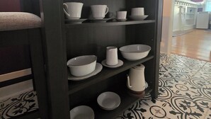 A dining area with a dark wooden buffet shelf holding white bowls and plates. - Historic Southtown Oasis (San Antonio)