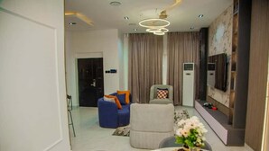 Una sala moderna con comedor, que incluye un juego de sofá, un televisor montado en la pared y un jarrón decorativo sobre la mesa de comedor.