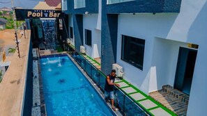 A swimming pool adjacent to a building with a sign reading "Pool Bar". - Aviv Luxury Homes (Enugu)