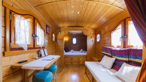 L’intérieur chaleureux d’un chalet, avec un décor en bois, un lit superposé, une petite table avec des chaises et une fenêtre avec des rideaux.