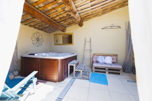 Zona de spa con jacuzzi, banco de madera y escalera.