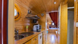 L’intérieur d’une cabane en bois comprend un coin cuisine équipé d’un évier, d’une cuisinière et d’un four à micro-ondes.