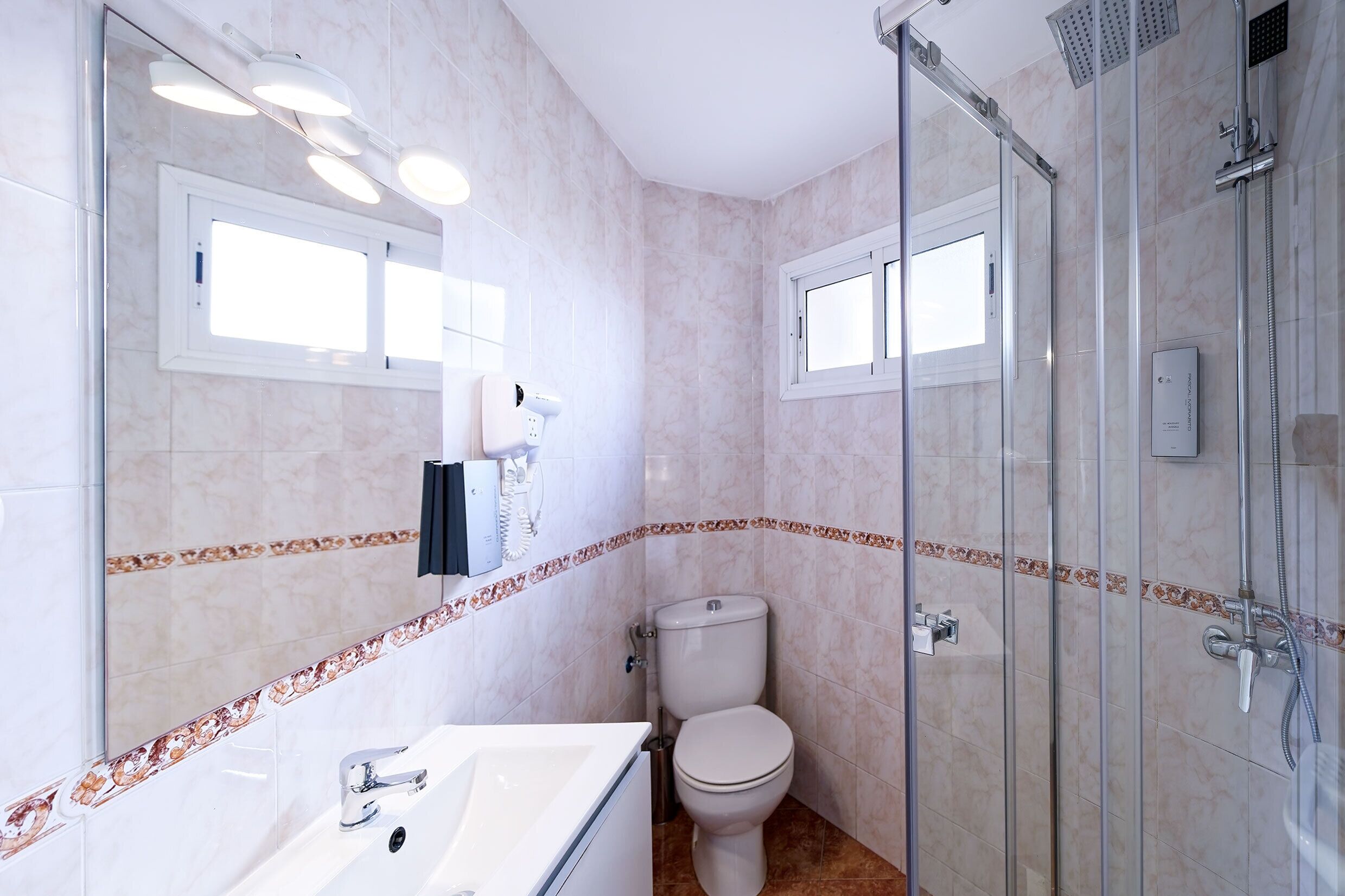 Un baño con cabina de ducha de vidrio, inodoro y lavabo con espejo.