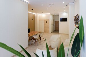 Un interior moderno con una mesa de comedor de madera, sillas blancas y un sillón grande tejido.