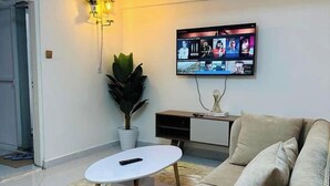 Un saló modern amb un sofà beix, una taula de centre blanca i un televisor de pantalla plana fixat a la paret.