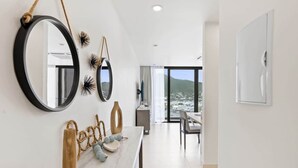 Habitación de hotel moderna con encimera de mármol, un espejo grande, decoración en la pared y vistas a un paisaje montañoso a través de amplias ventanas.