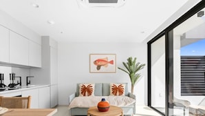 A modern kitchen with white cabinets, a dining table, and a sofa with decorative pillows.