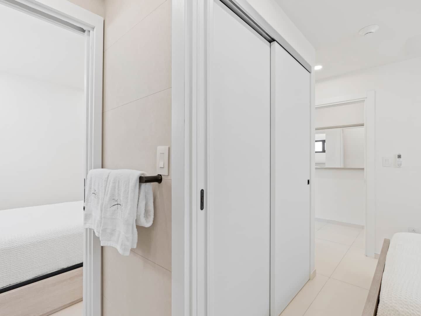 A modern hotel room with a bed, a bathroom with a toilet and sink, and a sliding door closet.