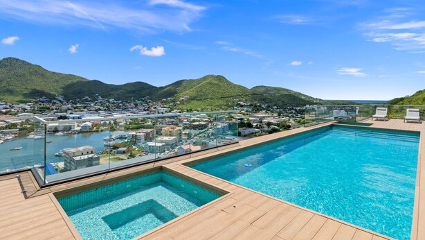 A swimming pool with a view of a coastal town and mountains.