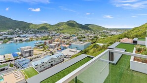 A coastal town with a marina, green hills, and modern buildings.
