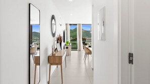 A modern hotel corridor with a view of a mountainous landscape through large windows. - D414 – 1-Bedroom Apartment with Balcony (Sint Maarten)