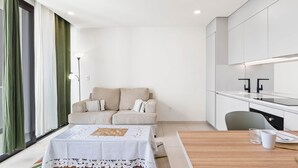 Une pièce moderne comprenant un canapé, une table à manger et un coin cuisine.