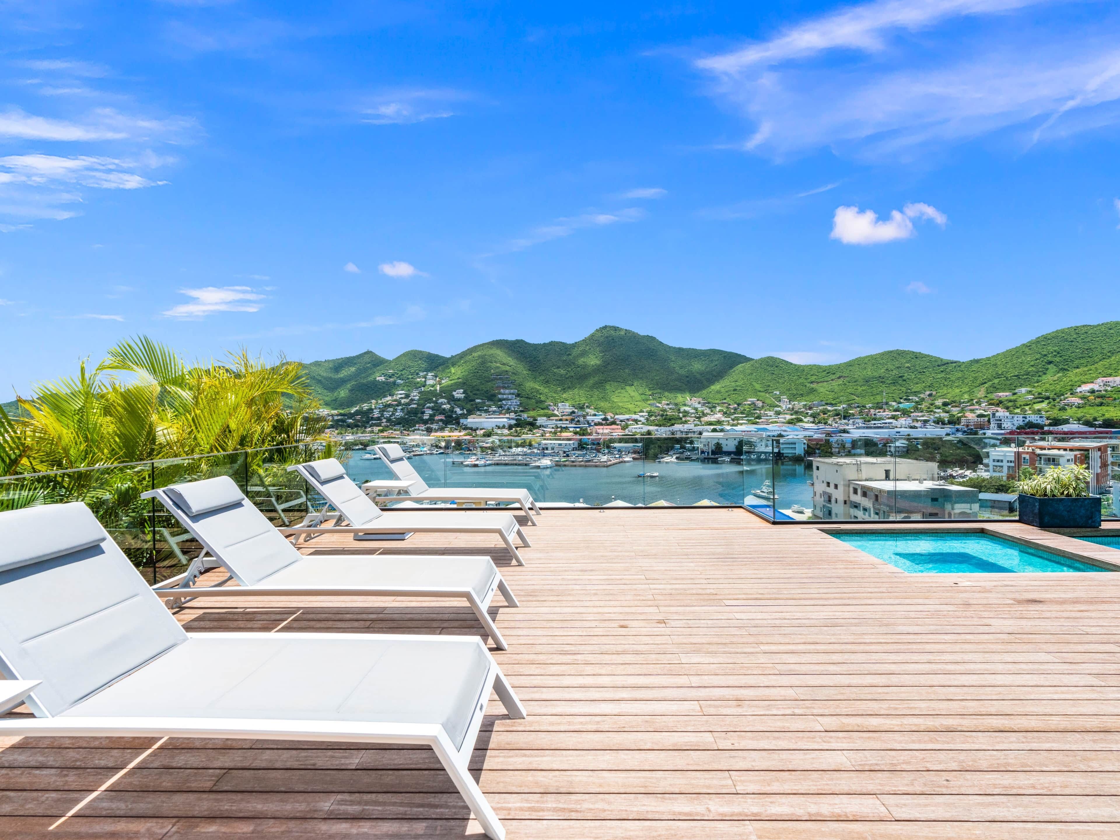 Une terrasse en bois avec des chaises longues donnant sur une marina et une ville.