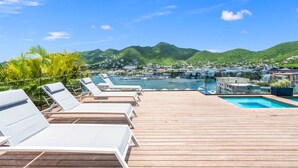 Une terrasse en bois avec des chaises longues donnant sur une marina et une ville.