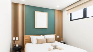 Une chambre moderne avec un grand lit, un lambris en bois sur les murs, un tableau encadré au-dessus du lit et une fenêtre sur le côté droit.