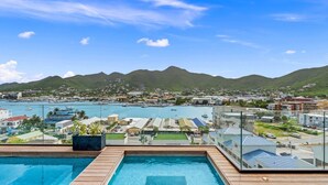 Un hôtel dot é d’une piscine offrant une vue sur un port de plaisance et les montagnes.