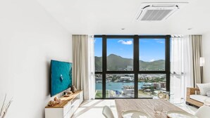 A modern hotel room with a large window offering a view of a city and hills. - C333 - Charming Apartment with Lagoon View (Sint Maarten)