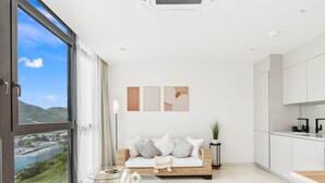 A modern living room with a large window, a glass coffee table, a sofa, and minimalist decor. - C333 - Charming Apartment with Lagoon View (Sint Maarten)
