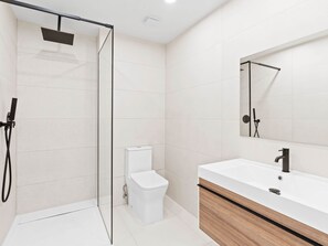 A modern bathroom with a glass-enclosed shower, a white toilet, and a wooden vanity with a white sink. - C314 - Stunning 1 Bedroom Apartment (Sint Maarten)