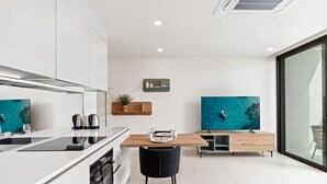 A modern kitchen with white cabinets, a black stove, and a wooden dining table.