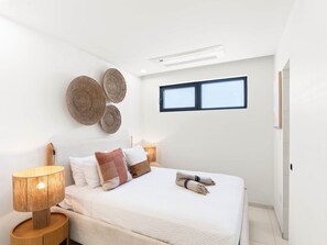 Een slaapkamer met een bed, nachtlampjes, een raam en wanddecoratie.