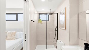 Een moderne badkamer met een douche, toilet en wastafel.