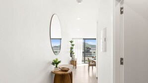 Un couloir moderne avec une table d’appoint en bois, un miroir et une vue sur un balcon agrémenté de plantes et d’un coin repas.