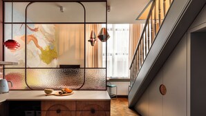 A modern kitchen with a wooden cabinet, a glass partition, and a colorful abstract painting. - Soho Residence Kazimierz by Downtown Apartments (Kraków)