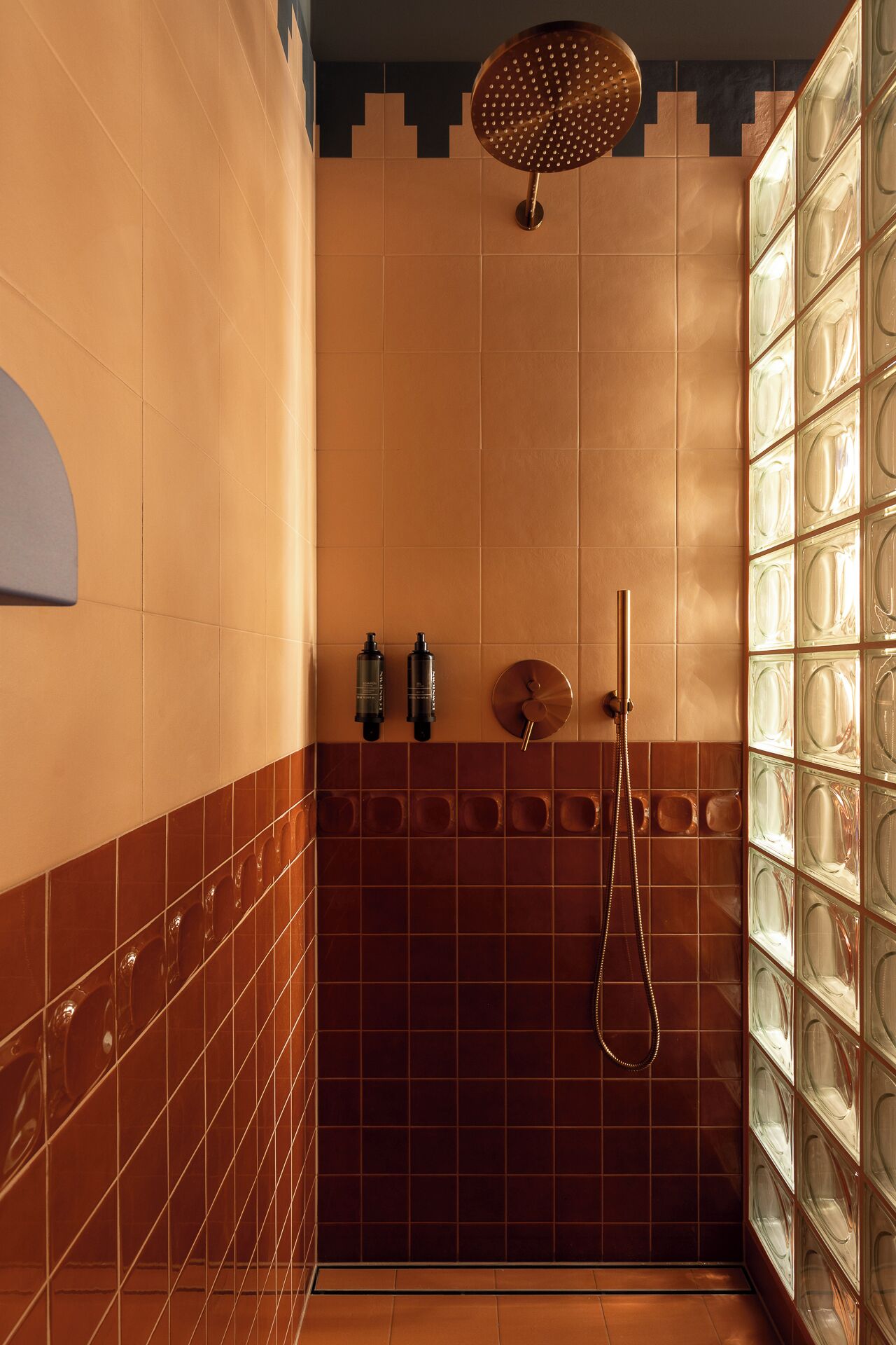 A bathroom with a shower, tiled walls, and a glass partition.