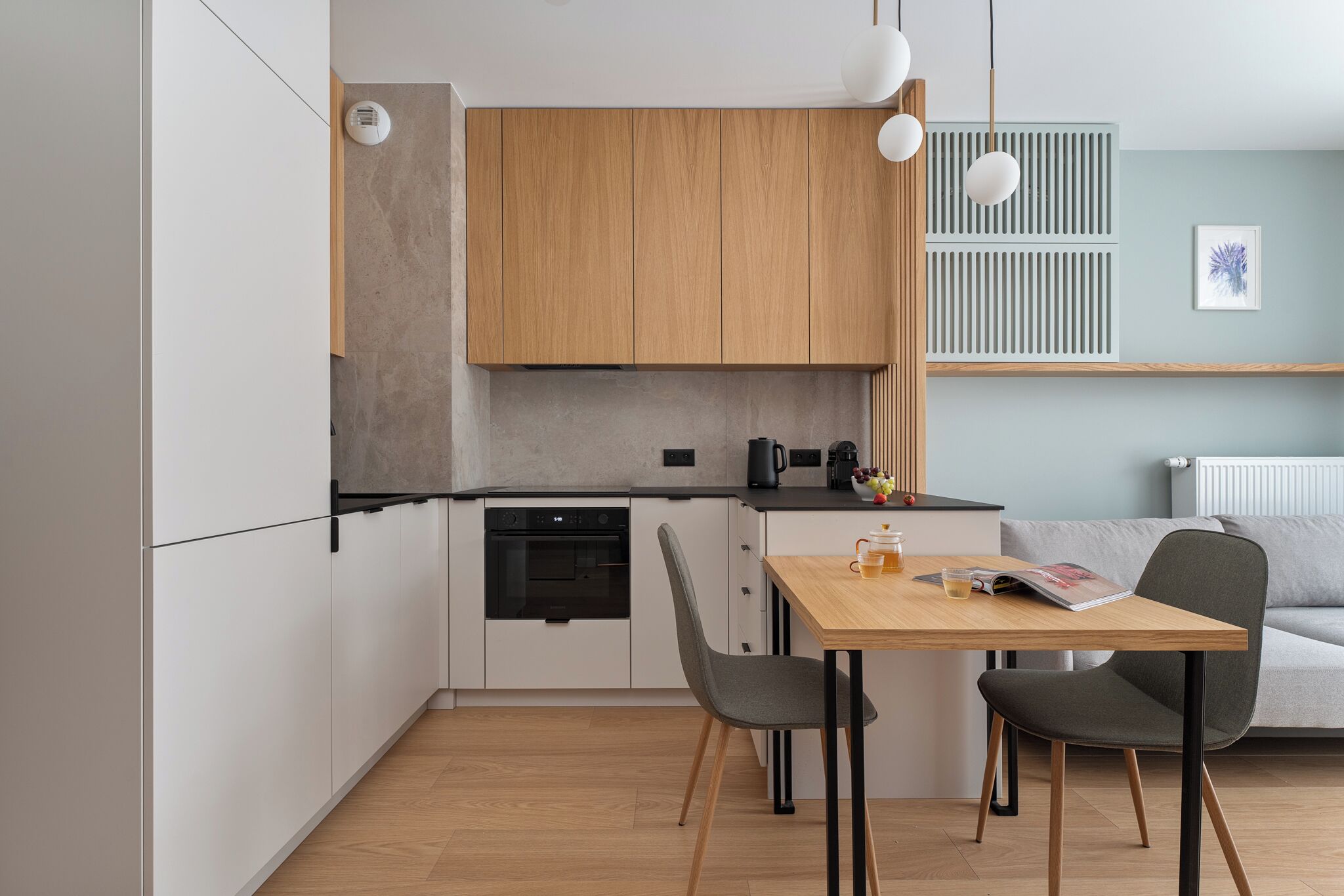 Una cocina moderna con armarios de madera, un horno negro y una mesa de comedor con sillas.
