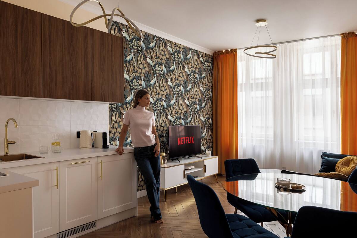 Una cocina moderna con un armario de madera, una encimera blanca y un televisor de pared que muestra el logotipo de Netflix.