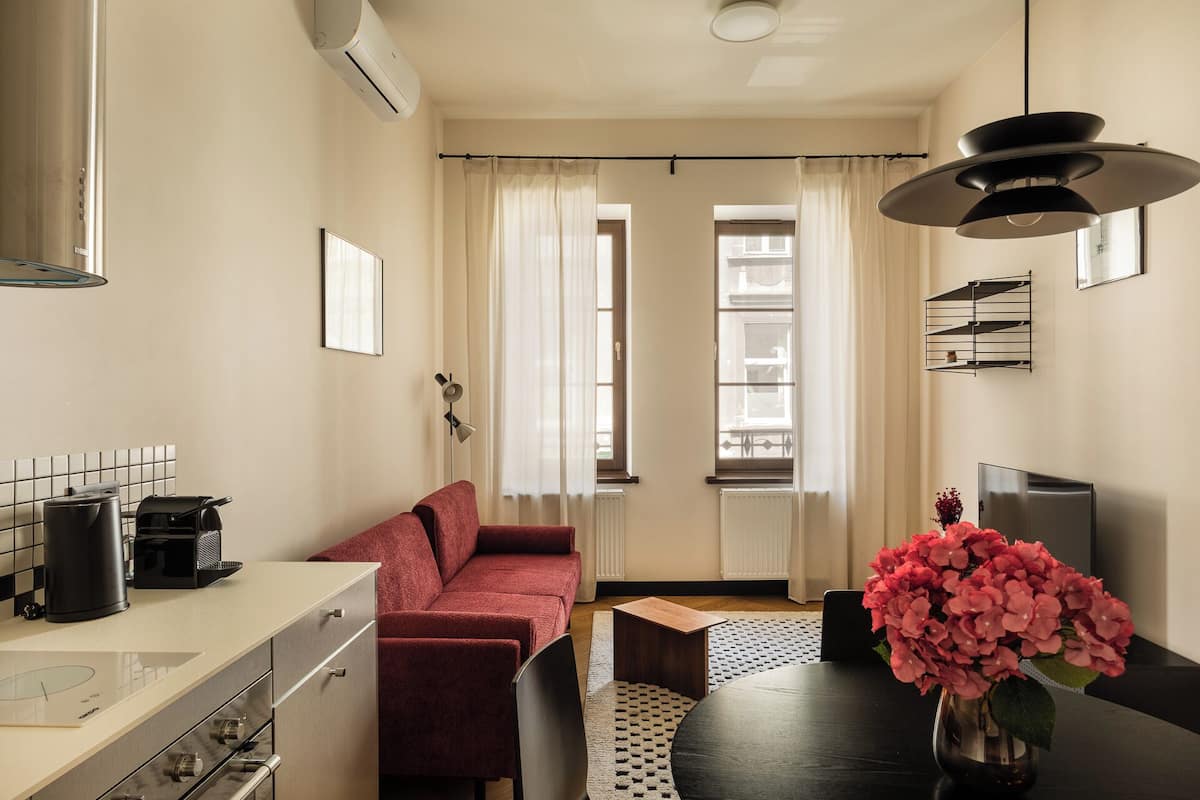 Una sala moderna con un sofá, una mesa de comedor con un florero, una máquina de café y un televisor.
