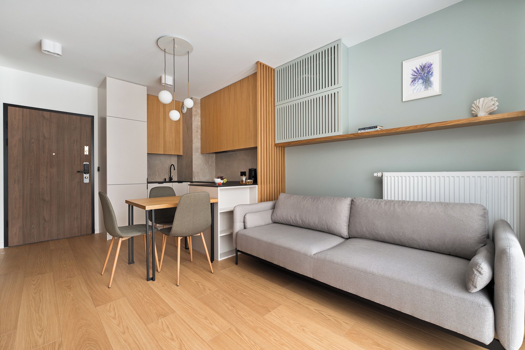 A modern living room with a grey sofa, wooden dining table, and chairs.