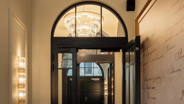A hallway with a black and white checkered floor, a chandelier, and a wall with handwritten text. - Soho Residence Kazimierz by Downtown Apartments (Kraków)