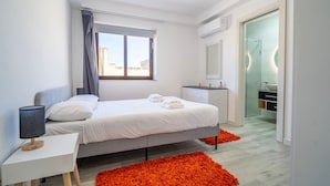 A modern bedroom with a bed, bedside table, and a bathroom visible through an open door. - Hal Wardija in Qala Gozo With Terrace Pool BBQ (Qala)
