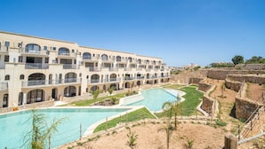 A hotel with multiple balconies, a swimming pool, and a landscaped garden. - Hal Wardija in Qala Gozo With Terrace Pool BBQ (Qala)