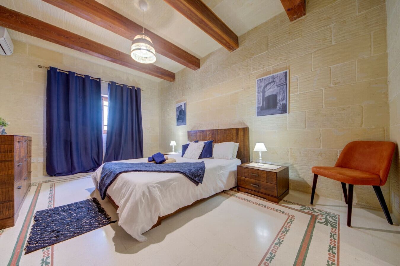 A bedroom with a bed, nightstands, a chair, and a large window with curtains.
