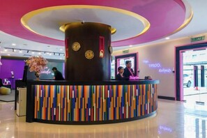 A reception desk with a clock, a counter, and a wall-mounted clock. - MagTree Chinatown (Kuala Lumpur)