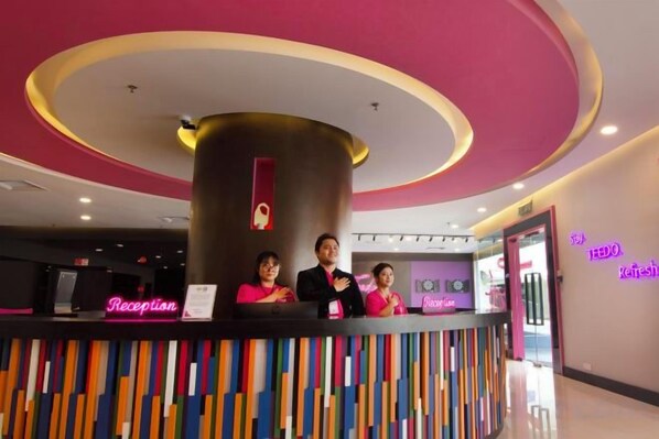 A reception desk with a neon sign, a pillar, and a colorful wall.