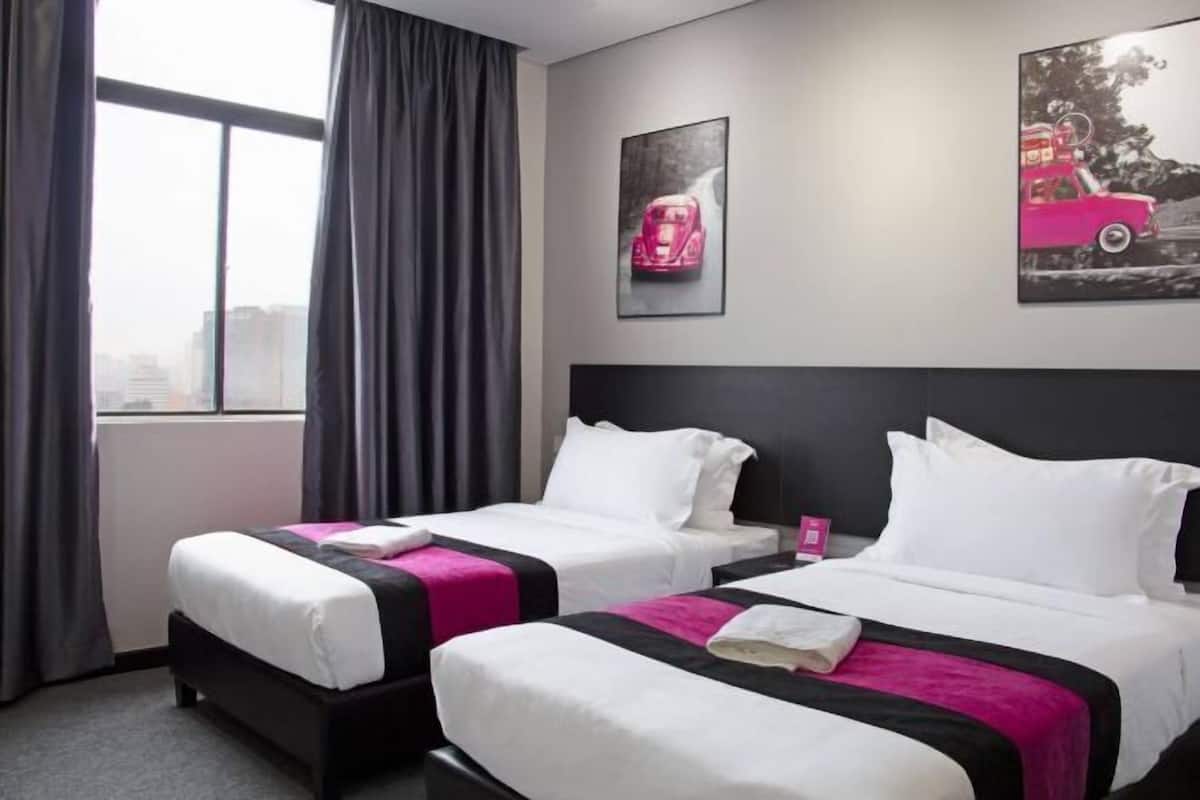 A hotel room with two beds, a large window, and artwork on the walls.