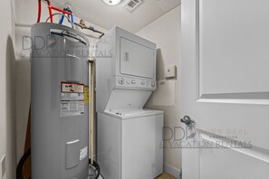 Een praktische bijkeuken met een boiler, een wasmachine en een droger.