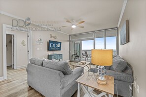 A modern living room with a grey sofa, a wooden coffee table, and a ceiling fan.