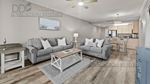 A modern living room with two grey sofas, a wooden coffee table, and a ceiling fan.