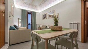 A dining area with a table, chairs, a sofa, and a plant. - Cozy apartment in the heart and historic center of Palermo. (Palermo)