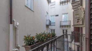 A narrow urban alleyway with a metal railing, potted plants, and a building with multiple balconies. - Cozy apartment in the heart and historic center of Palermo. (Palermo)