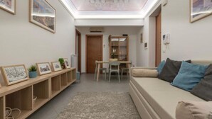 A modern living room with a sofa, a dining table, and a hallway leading to another room. - Cozy apartment in the heart and historic center of Palermo. (Palermo)
