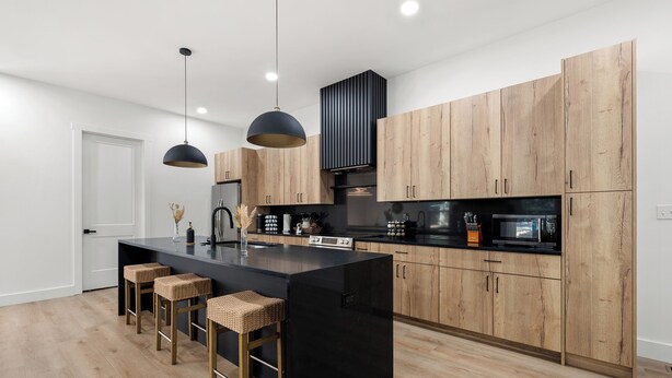 Una cucina moderna con un'isola grande, mobili in legno e luci a sospensione.
