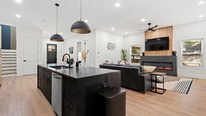 Una cucina moderna con isola centrale, mobili neri e illuminazione a sospensione.