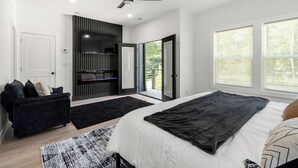 Una camera da letto moderna con un letto, un divano nero, una TV e una ventola a soffitto.